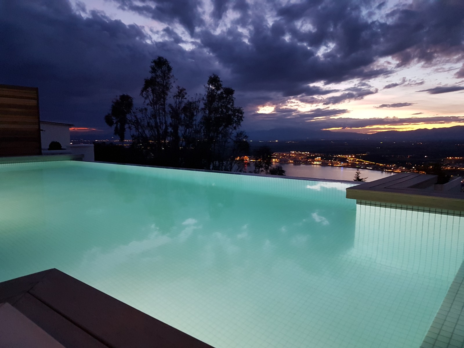 Illuminated infinity pool at twilight with city lights below